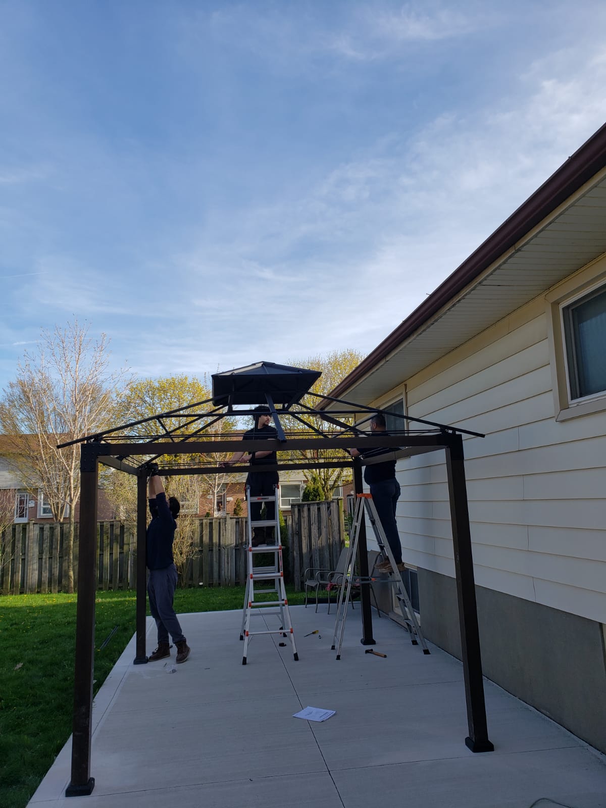 Newly installed hardtop gazebo with mosquito netting in a backyard